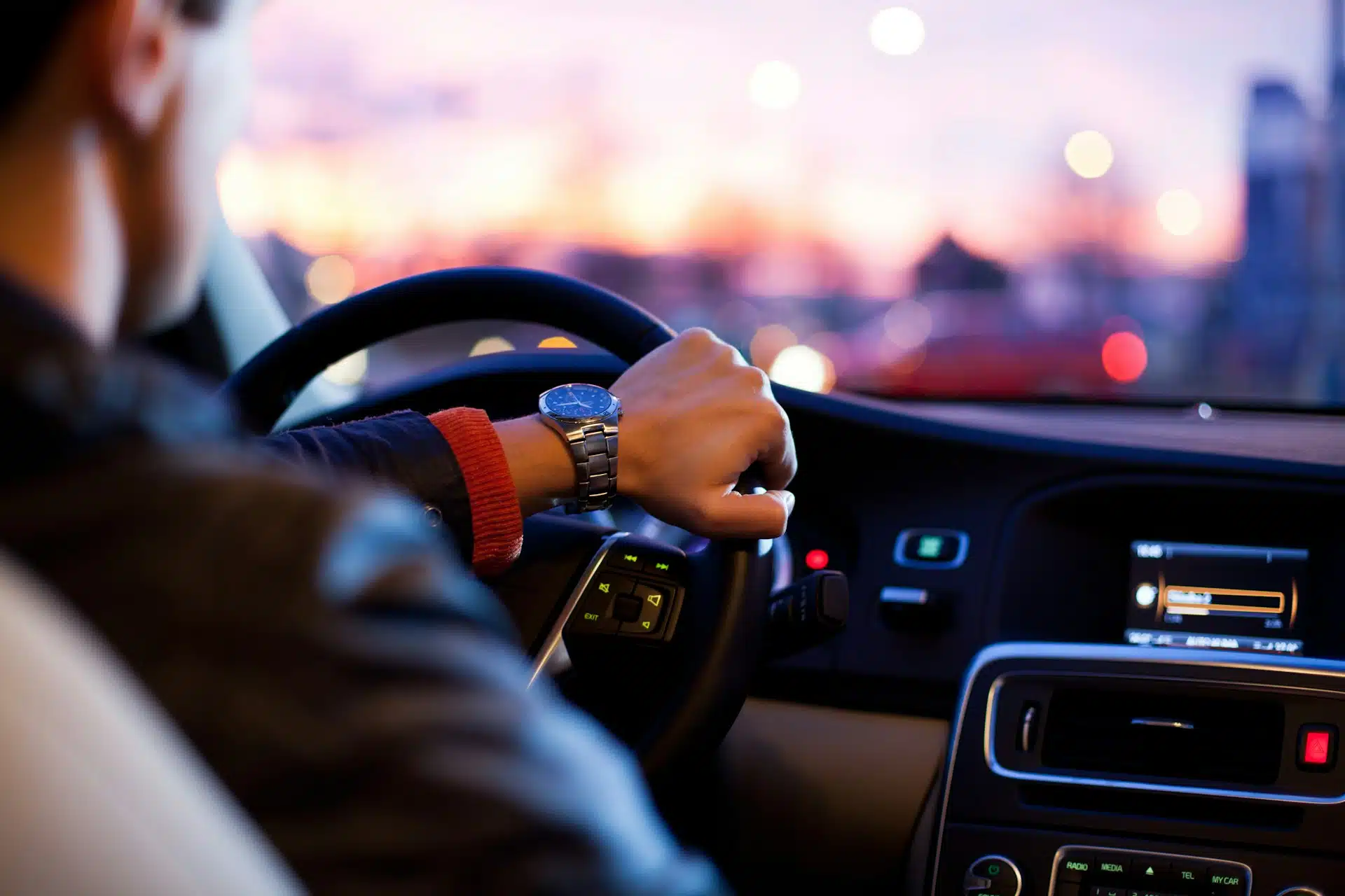 hombre conduciendo un coche con la mano en el volante