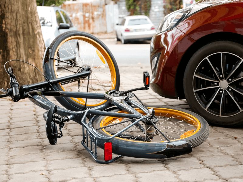 a bicycle on its side in front of a red car