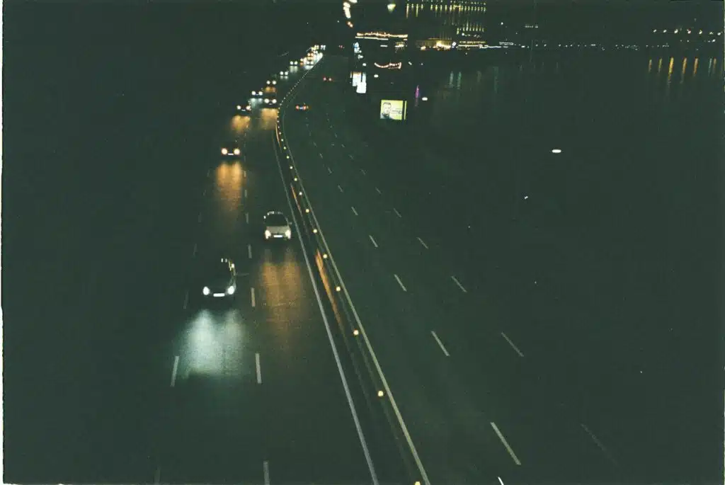 Una escena nocturna en la autopista con coches circulando, iluminada por las farolas y los faros.
