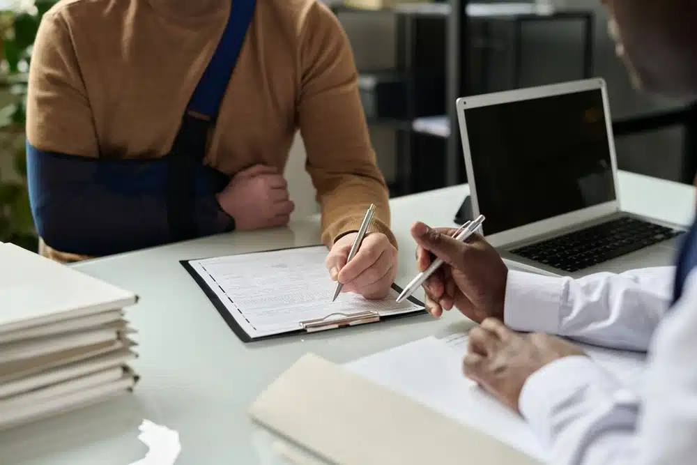 A man with a broken arm sits at a desk with a lawyer, discussing personal injury legal matters.